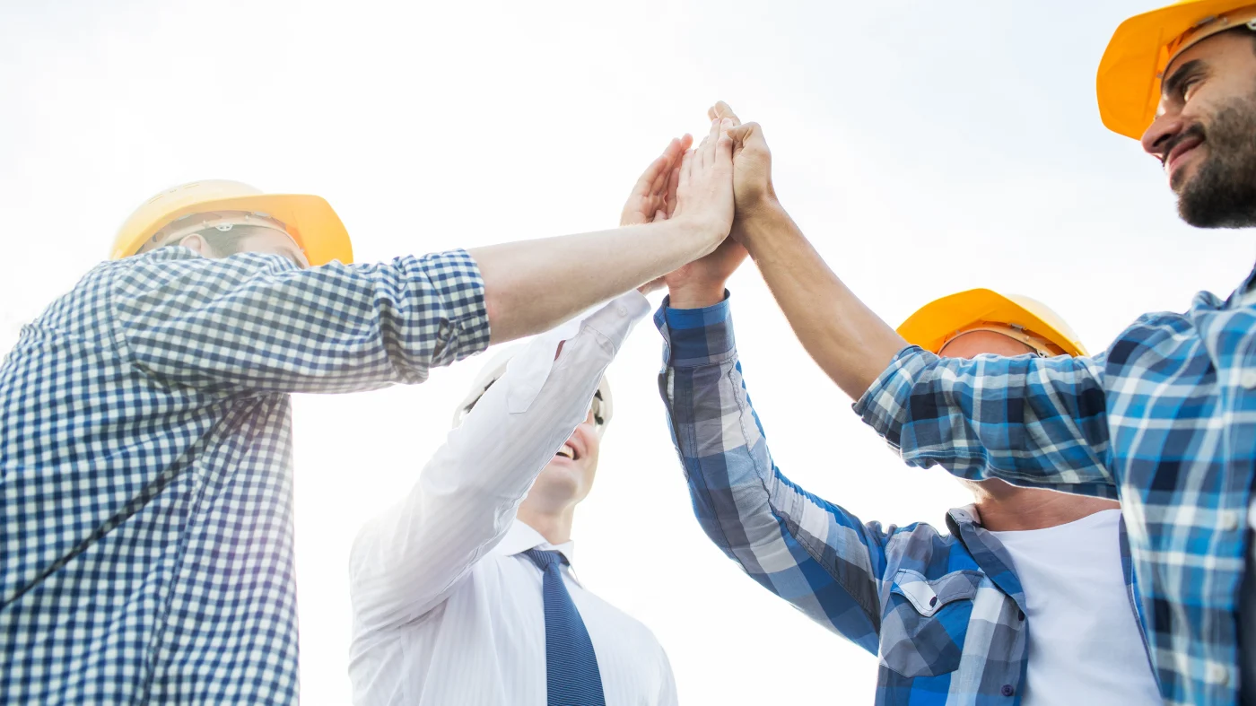 A group of roofing contractors high fives one another