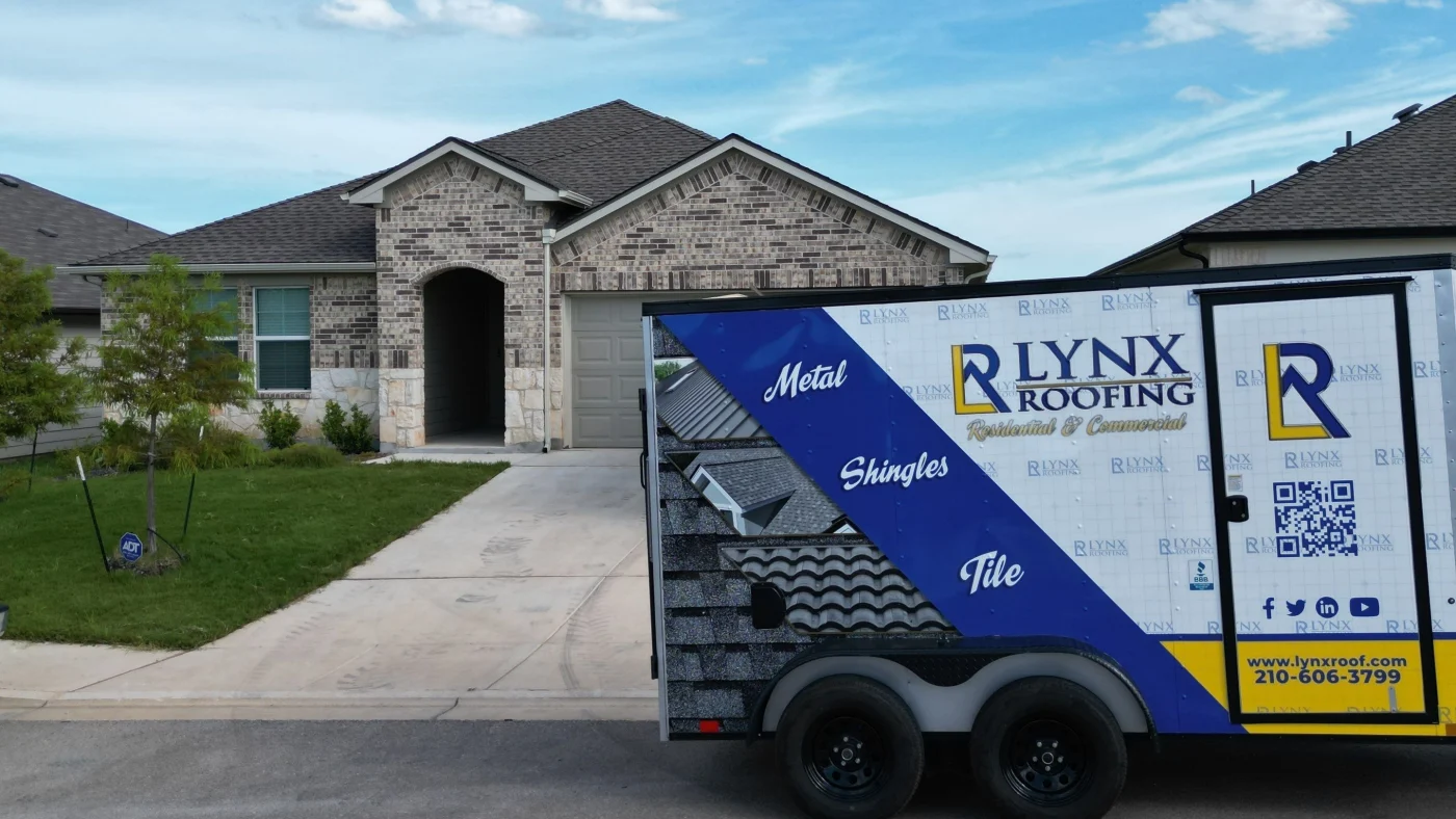 A home with stone siding and a new shingle roof with a Lynx Roofing trailer parked in front