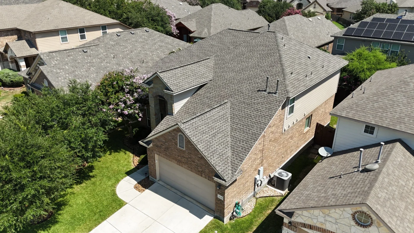 A home with tan brick siding and a gray shingle roof