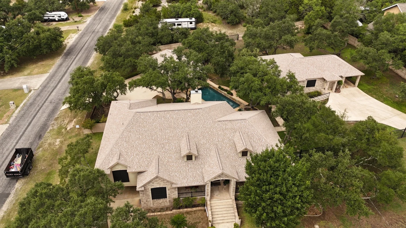 A large home with tan brick siding and a brown shingle roof