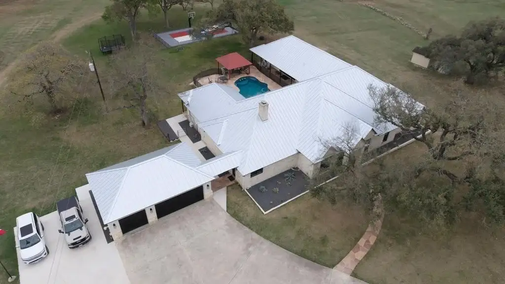 Exceptional Metal Roofing Services | North San Antonio, TX | Lynx Roofing, LLC Aerial view of a large home with a bright white metal roof and attached garage.