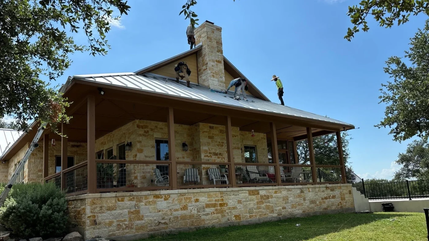 Exceptional Metal Roofing Services | Stone Oak | Lynx Roofing, LLC Roofing crew installing a silver standing seam metal roof on a stone home.